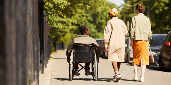 Inclusive group of friends, including a wheelchair user, enjoying a sunny day outdoors in community connection