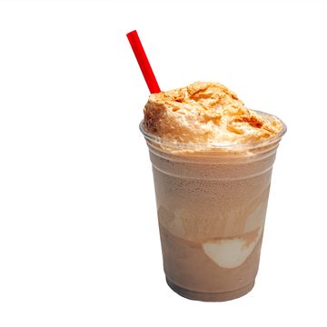 Chocolate milkshake with whipped cream and a red straw in a clear plastic cup.