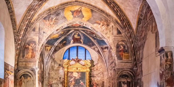 Interior of a historic church with frescoes and wooden pews.