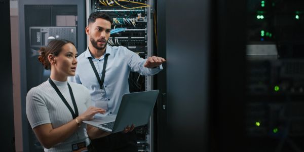 Two tech professionals working in a server room.