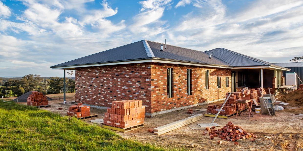 Brick house under construction with scattered materials.