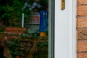A person peeks through a partially open glass door.