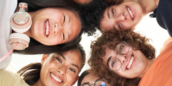 Healthy children, teens and tweens standing in a circle looking down at a camera and smiling