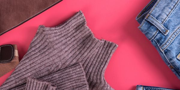 Flat lay of casual clothing items on a vibrant pink background.
