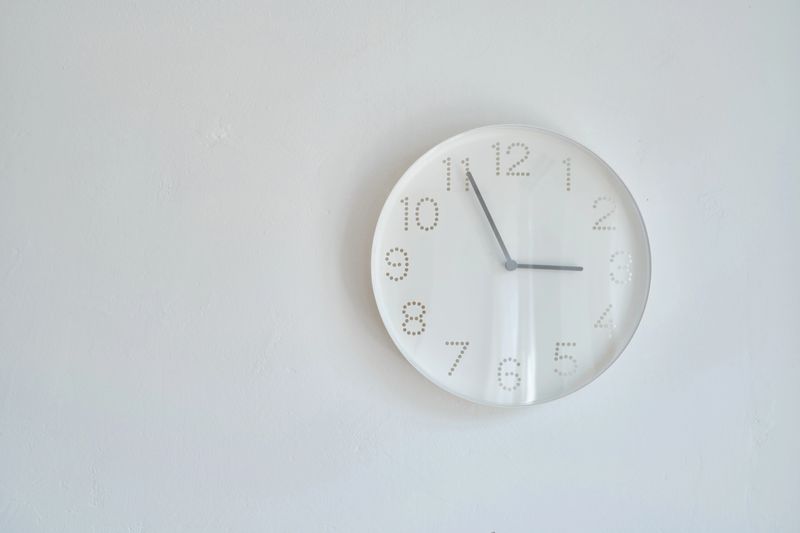 White round wall clock hanging on the wall. A minimalistic image of a wall clock on a white background with copy space. Scandinavian style in the room