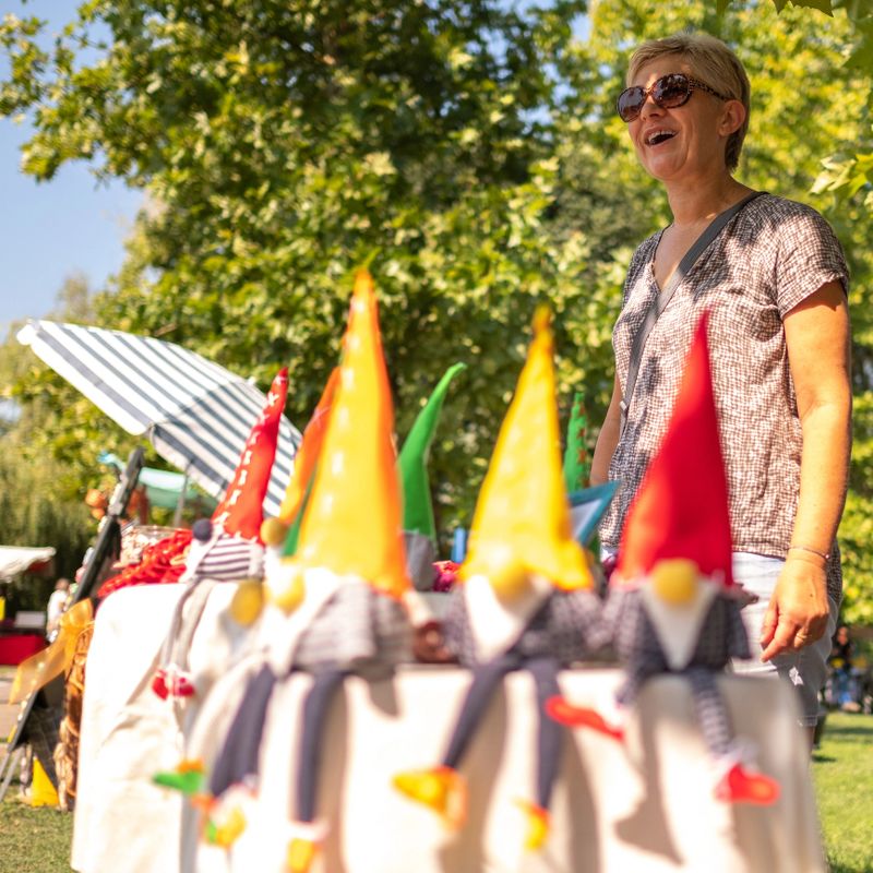 Middle age woman smiling and selling handmade crafts at street market