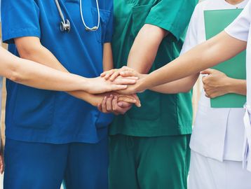 Staff Attack/ Nurse Call System. Image shows healthcare professionals holding hands.
