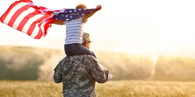Father carring boy on shoulders and boy is holding a USA flag