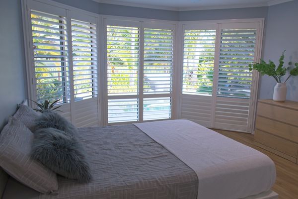 Bedroom with white plantation shutters.