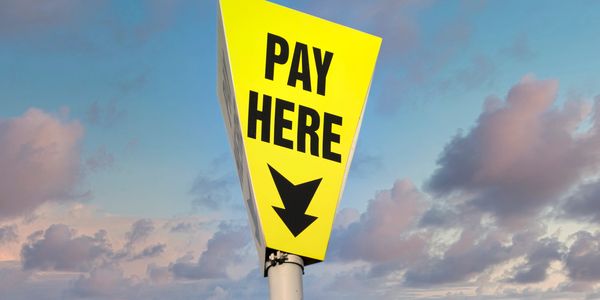 Bright yellow sign with 'PAY HERE' text and arrow.