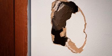 "Interior wall with large hole and peeling paint beside door frame with chipped paint, before paint.