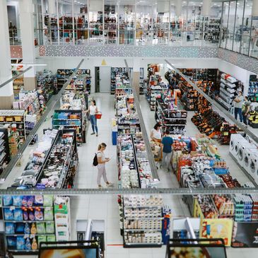 A spacious supermarket with multiple aisles and shoppers browsing products.