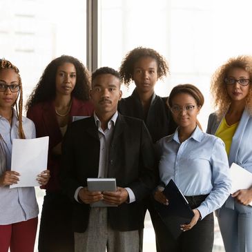 A diverse group of six professionals posing confidently in an office setting.