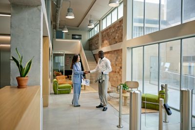 Two professionals shaking hands in a modern office lobby.