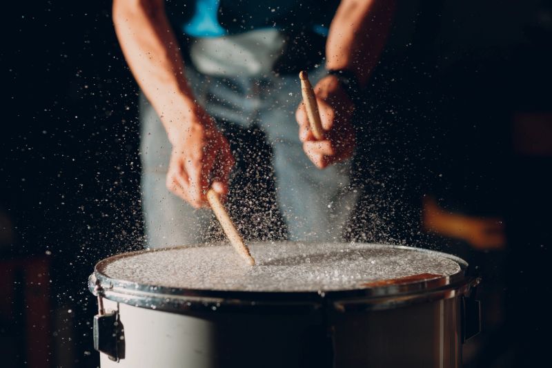 Close up drum sticks drumming hit beat rhythm on drum surface with splash water drops