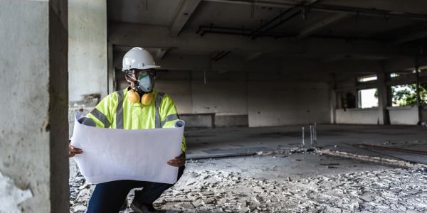 Construction worker inspecting a site with blueprints.