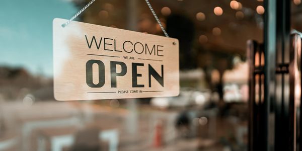 Window of a small business with Welcome/Open sign in it.