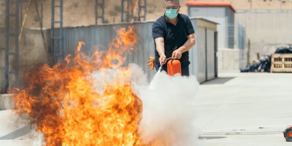 Man extinguishing fire with fire extinguisher.