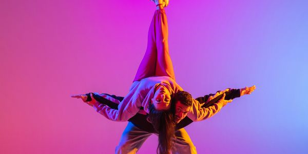 Two dancers performing an acrobatic pose with colorful lighting.