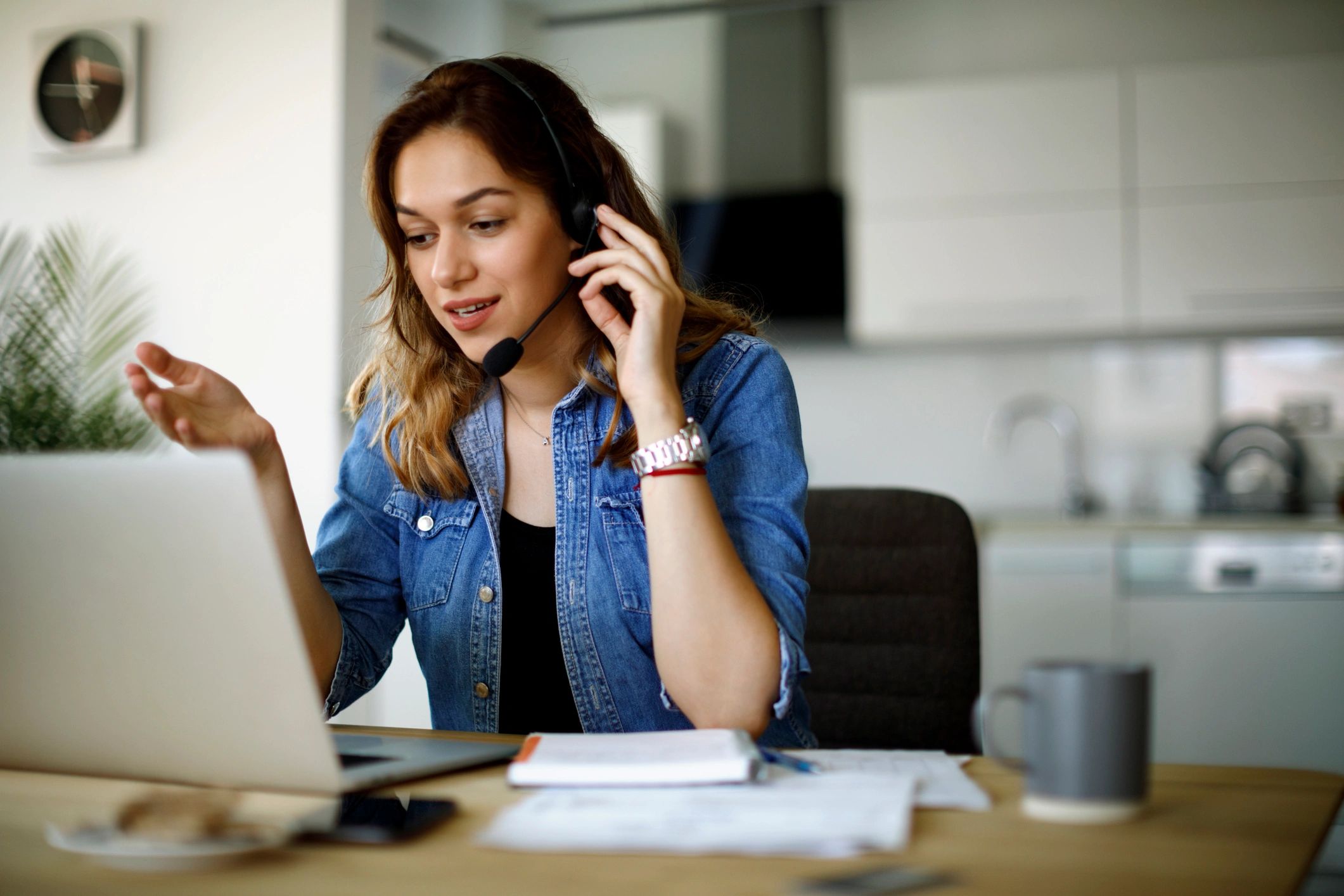 Young woman wearing headset, engaging in a video call at home.