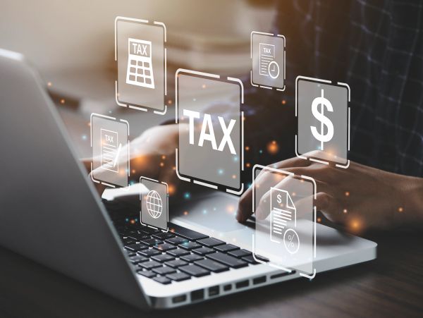 Person using laptop with digital tax and finance icons floating above keyboard.