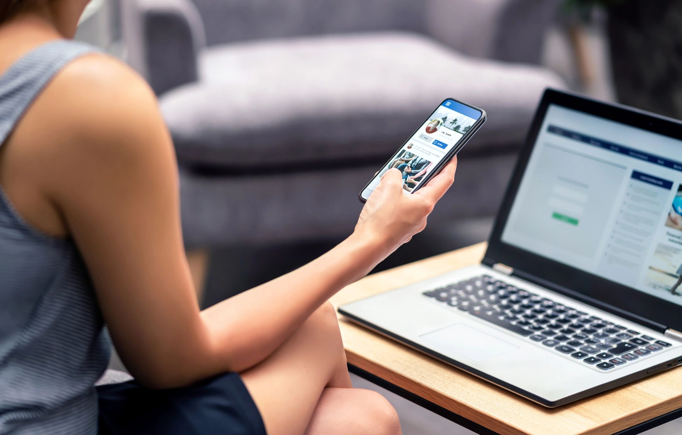 Person using smartphone and laptop at home.