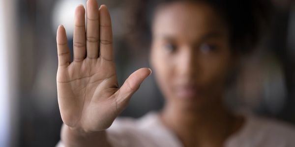 Woman with hand raised in a stop gesture.
