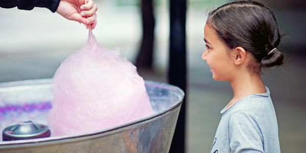 A girl excitedly watches as cotton candy is made.