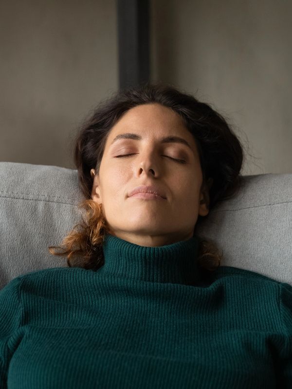 Woman relaxing with eyes closed on a couch.