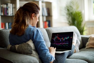 Woman analyzing stock market charts on her laptop at home.
