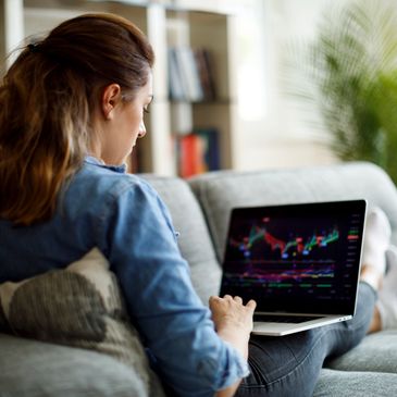 Woman analyzing stock market charts on her laptop at home.