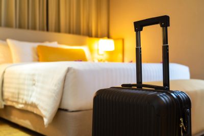 Black suitcase by a bed in a hotel room.