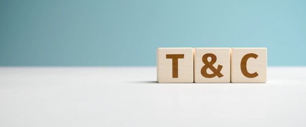 Wooden blocks spelling out T &amp; C on a white surface with blue background.