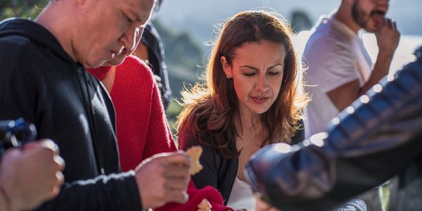People gathered outdoors, focused on food and conversation.