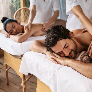 A couple enjoying relaxing massages on separate tables in a spa.