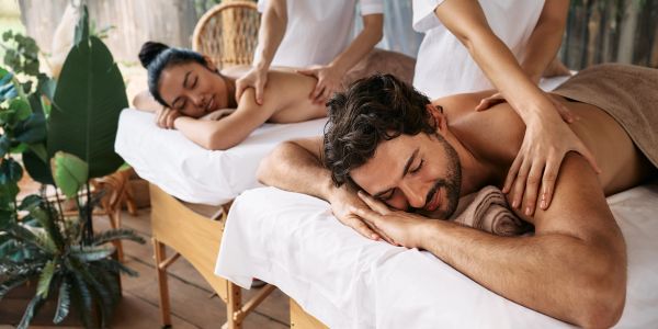 Couple receiving massages in spa.