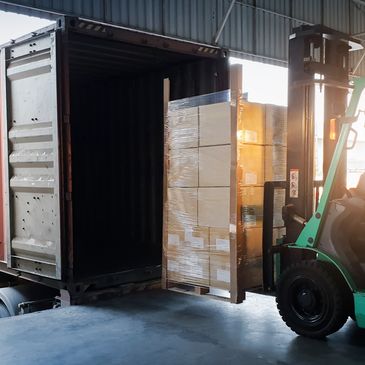 Forklift loading pallets into a shipping container.