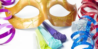 Colorful party mask with streamers and noisemakers on a white background.