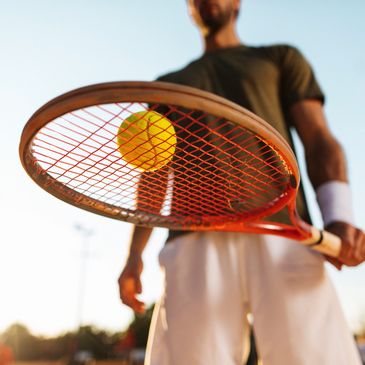 Tennis player holding racket with ball.
