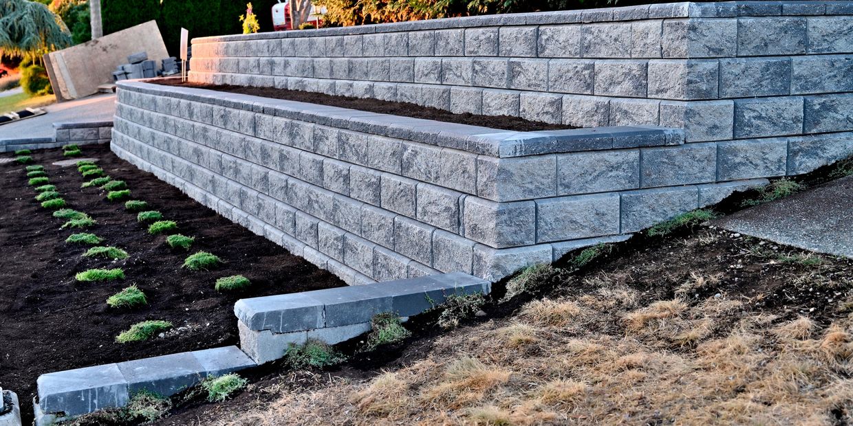 Newly built two-tier stone retaining wall in a landscaped garden.
