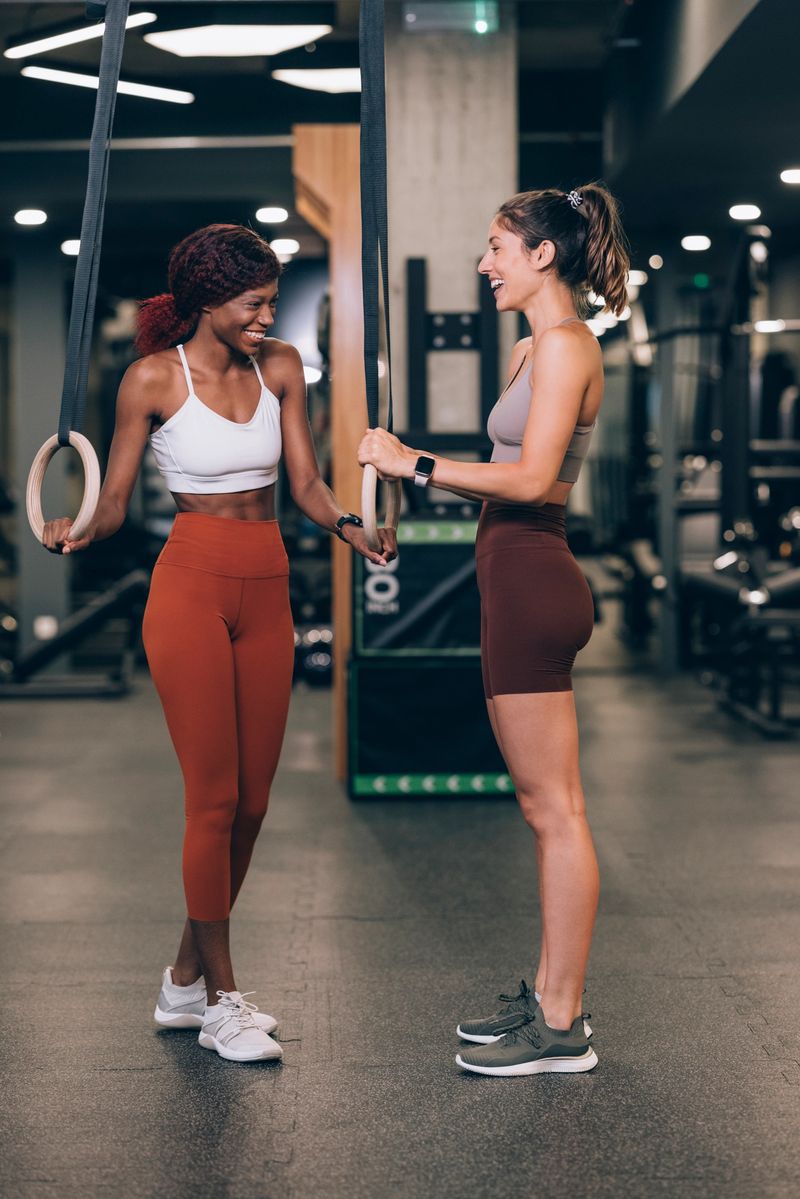 Two motivated sportswomen working out on gymnastic rings at the gym