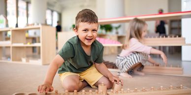 A boy happily playing with wooden toys indoors.