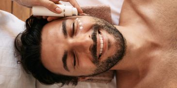 Man applying skincare cream and smiling.
