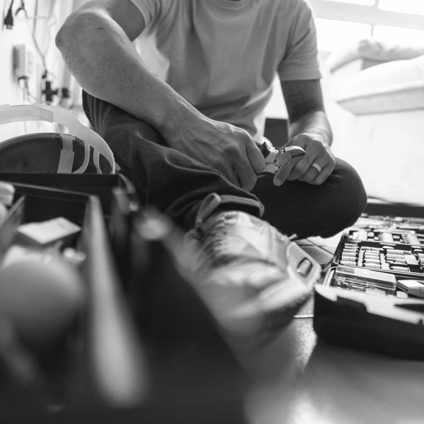 Man in yellow shirt sitting on floor with tools and pliers.