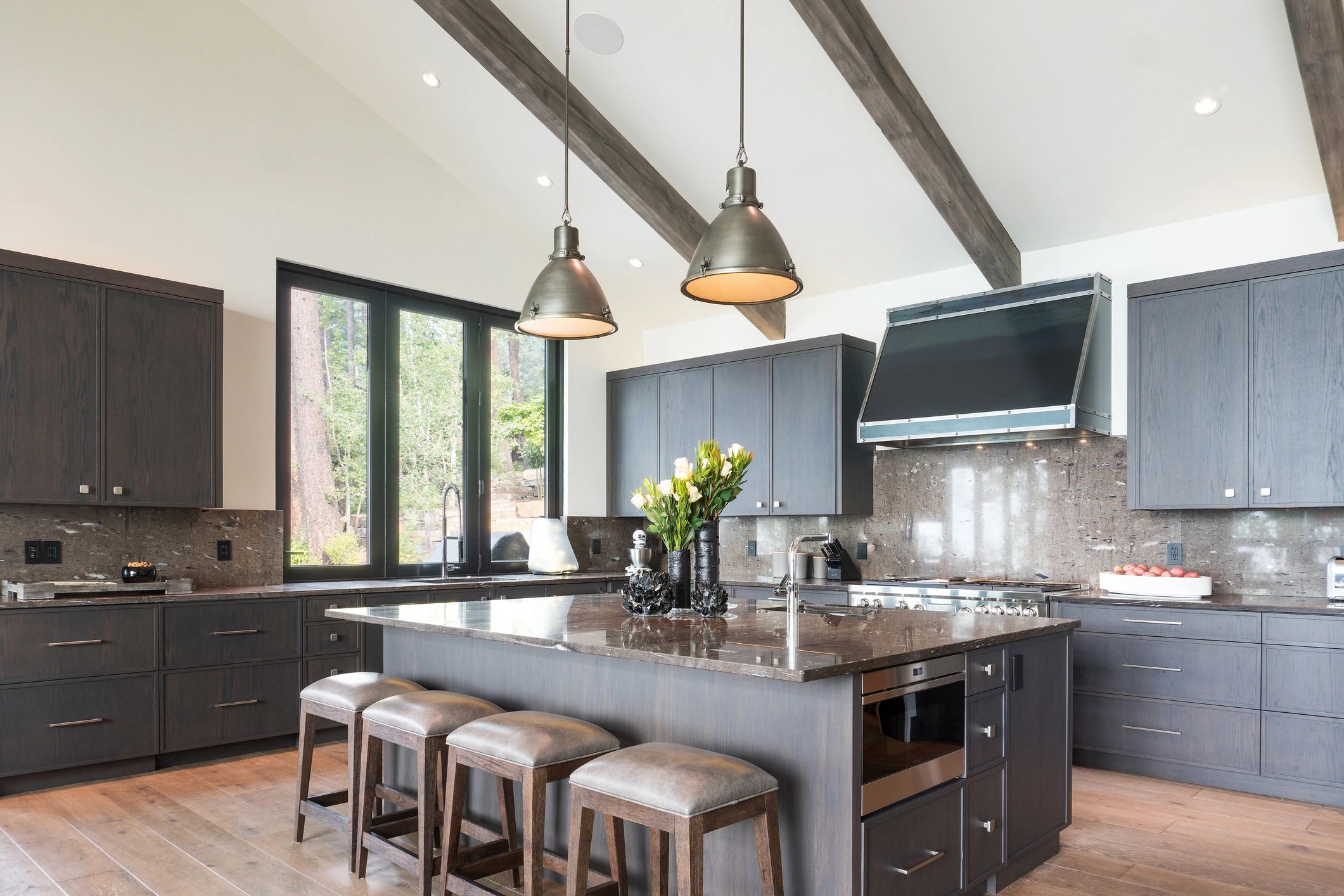 Modern kitchen with dark wood cabinets, marble countertops, and pendant lighting.