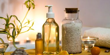 Spa essentials including oil, bath salts, and candles arranged on a wooden surface.