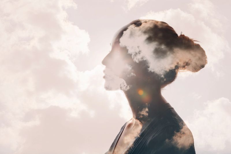 Psychology and woman mental health concept. Multiple exposure clouds and sun on female head silhouette.