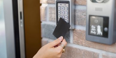 Hand using a key card on a keypad access system.