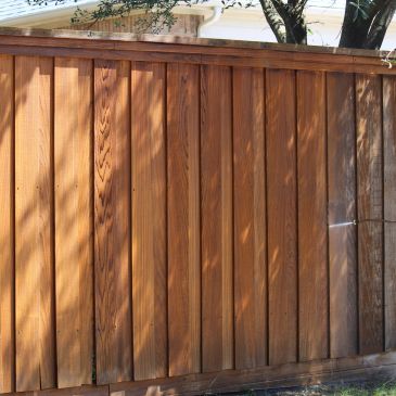 Wooden fence with sunlight and shadows from nearby trees.