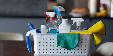 A basket filled with various cleaning supplies on a table.